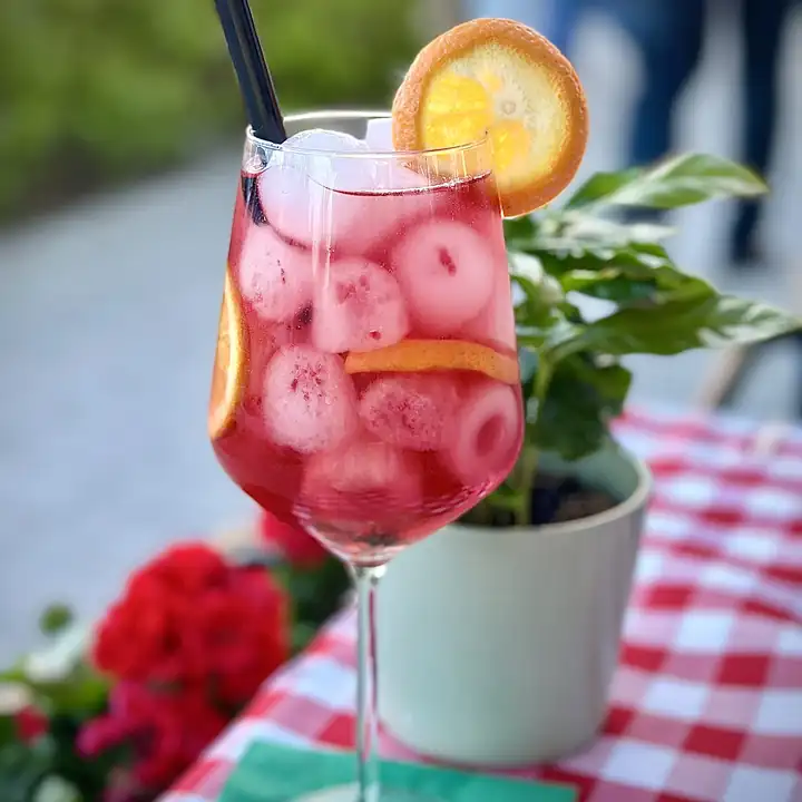 Różowy drink z pomarańczą na stoliku w kratkę